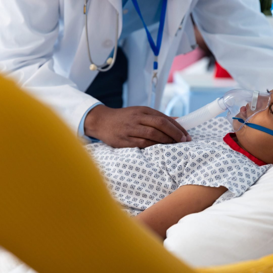 African american male doctor and mother beside son patient on ventilator in hospital bed. Hospital, medical and healthcare services.